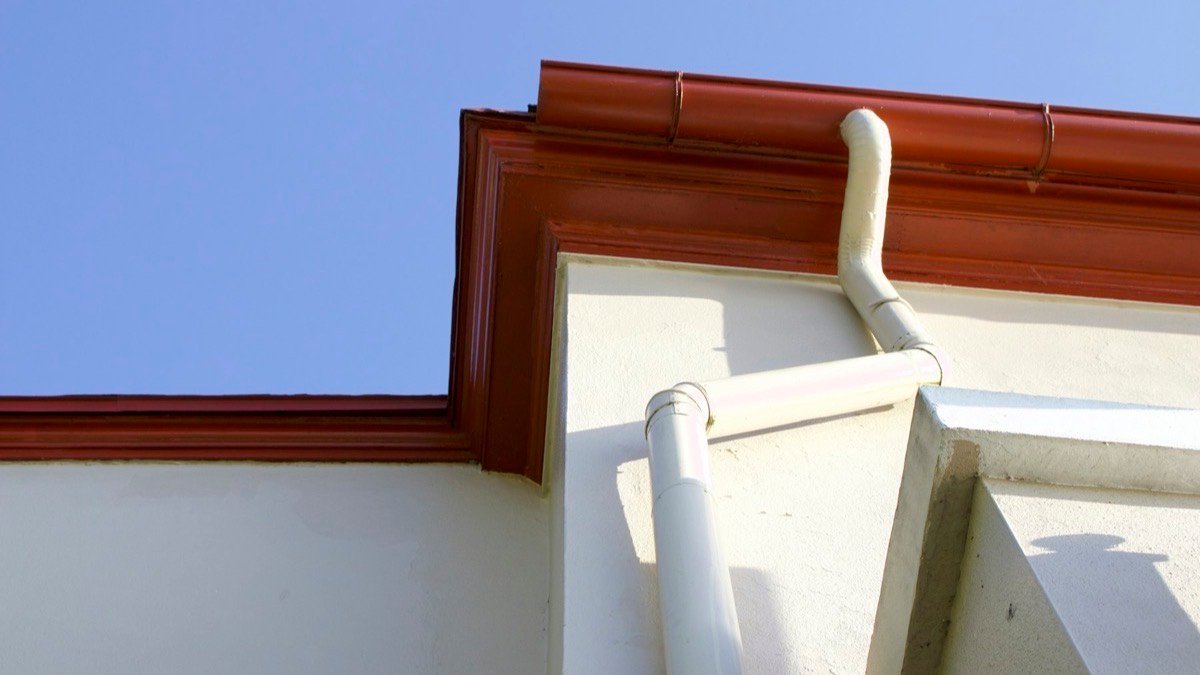 Gutter and downspout at the corner of a house roofline