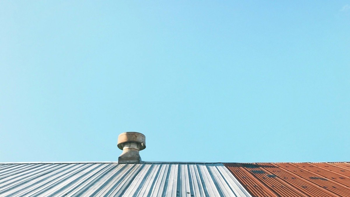 Roof vent installed on a metal roof against an overcast sky