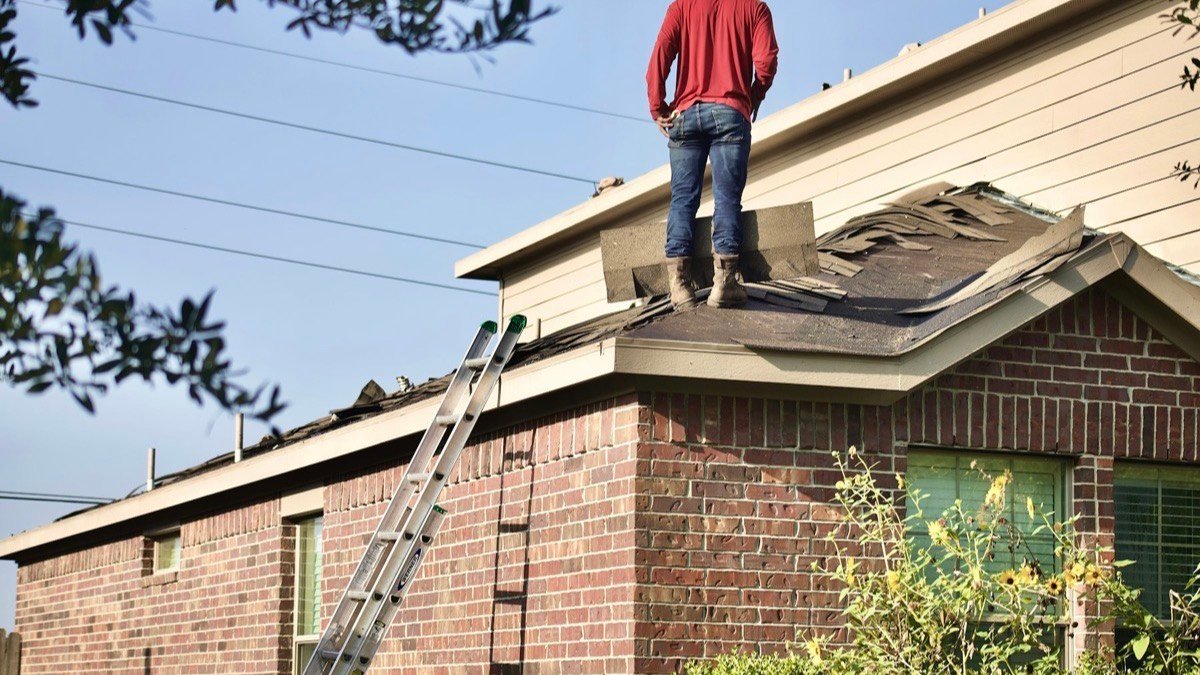 Roofer standing on the sloped roof of a brick house