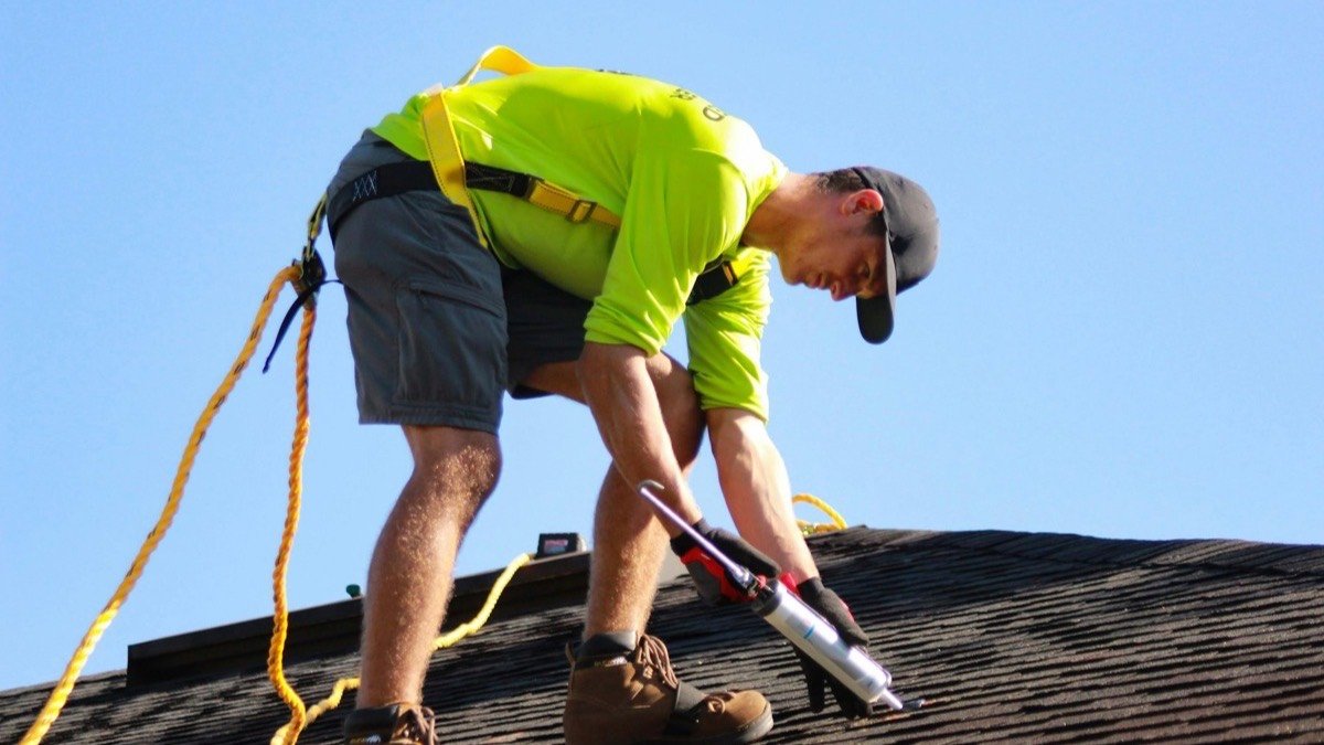 Roofer using a pry bar to lift worn shingles on a residential roof
