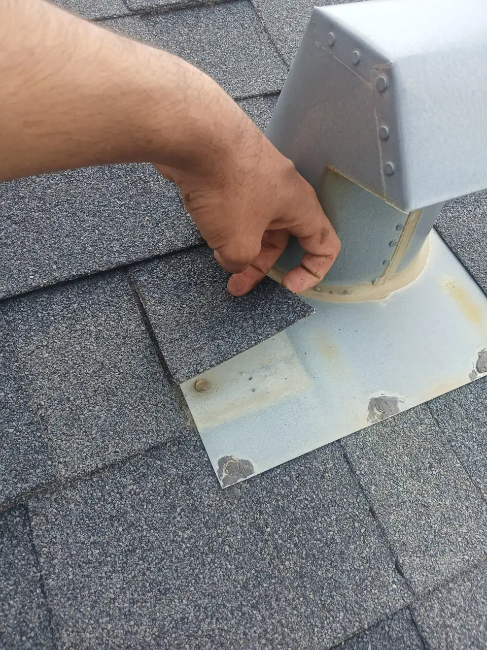 Roofer inspecting and sealing a shingle roof on an Edmonton home